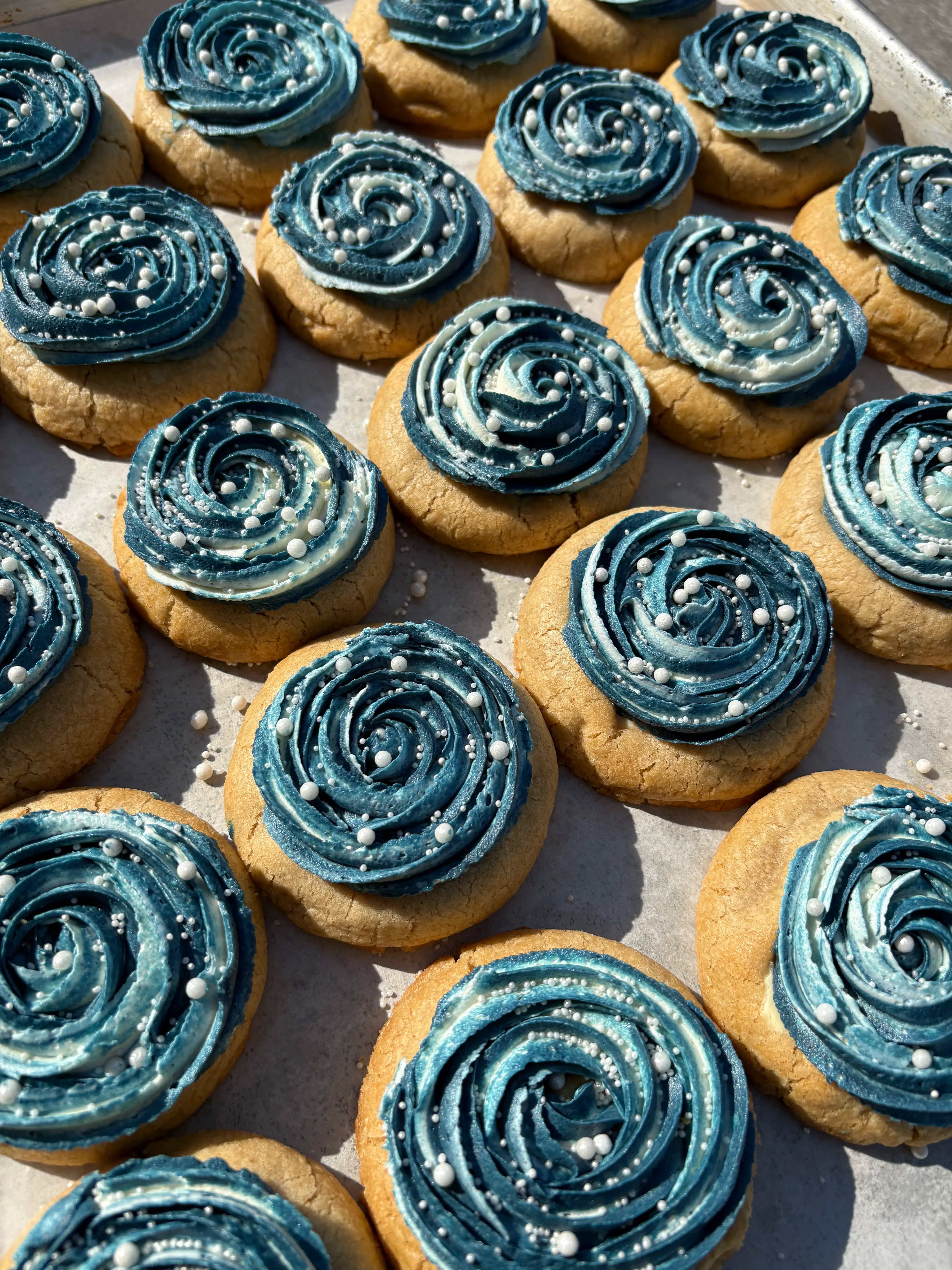 Cookies decorated with blue swirl frosting and pearl candies